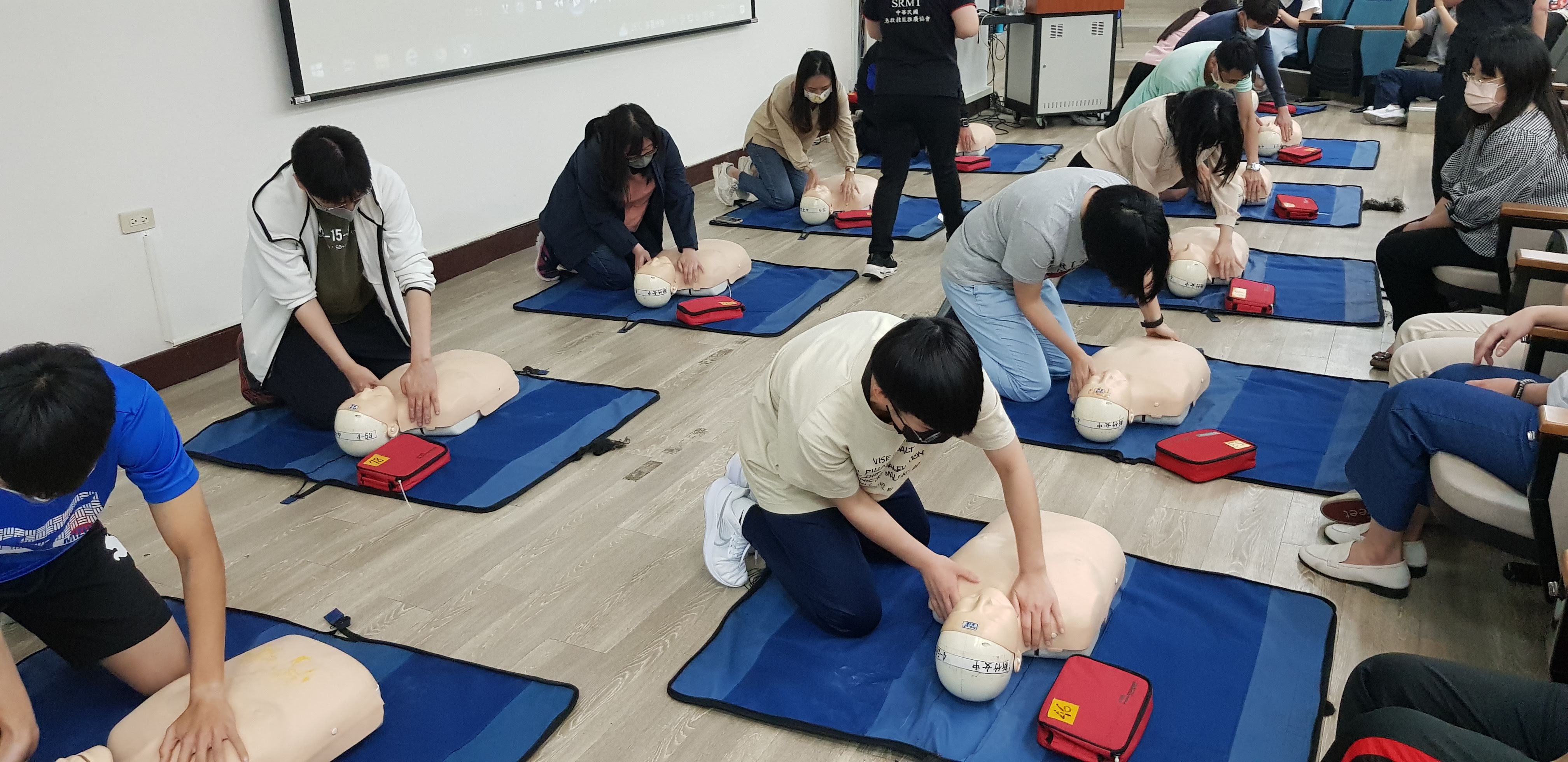 多位教職員工面向安妮模型進行 CPR 心肺復甦術的實作練習。