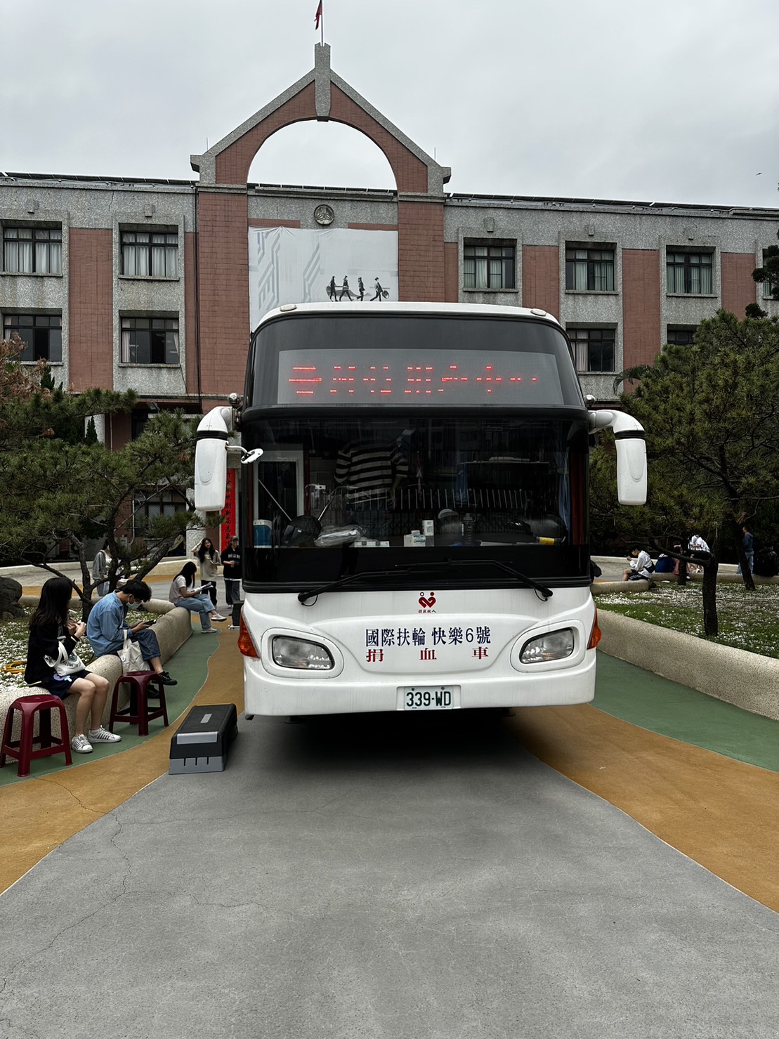 一輛大型白色捐血車停放在校園前校門廣場。