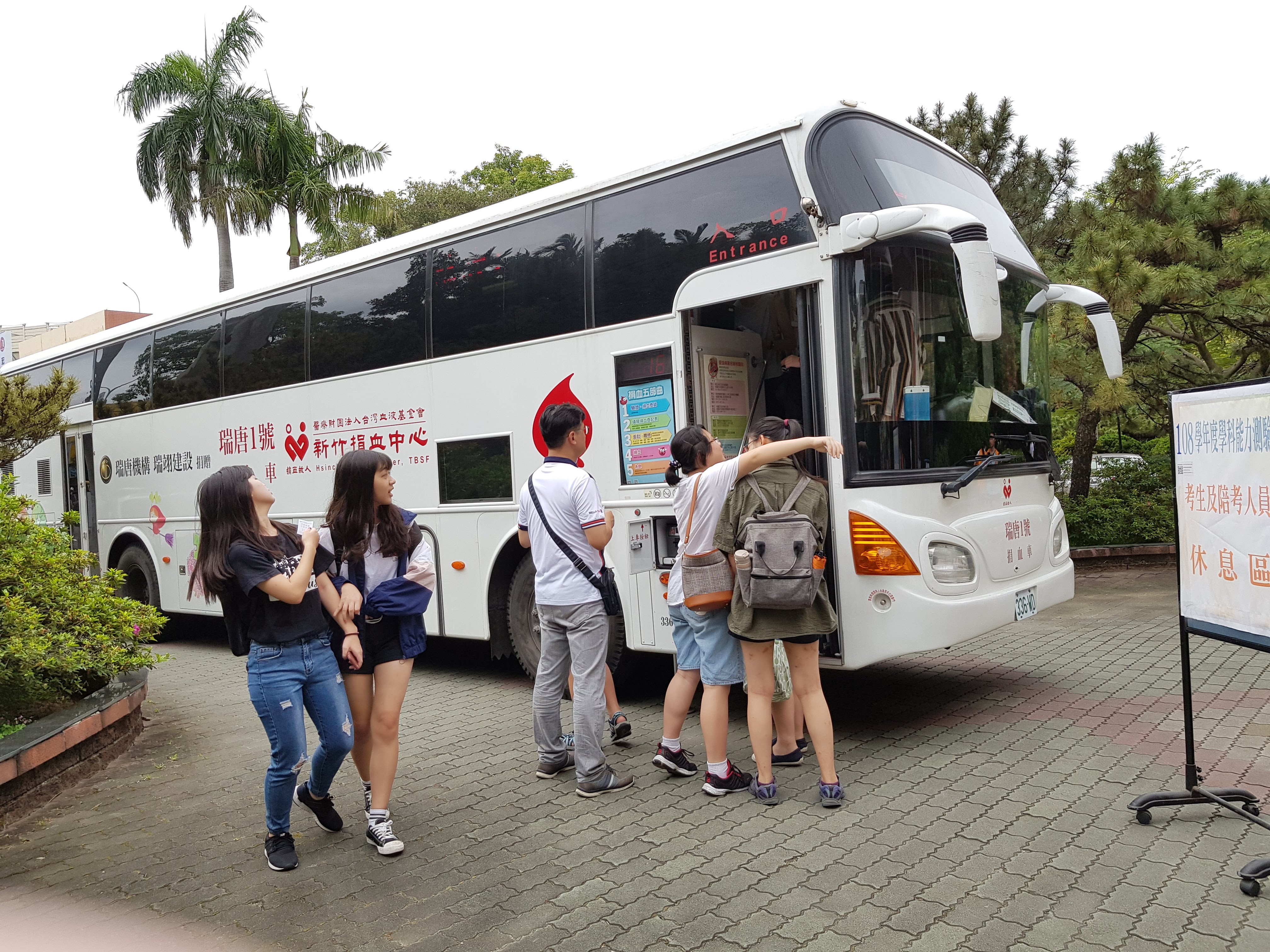 數名學生在捐血車外排隊，等候上車參與捐血活動。