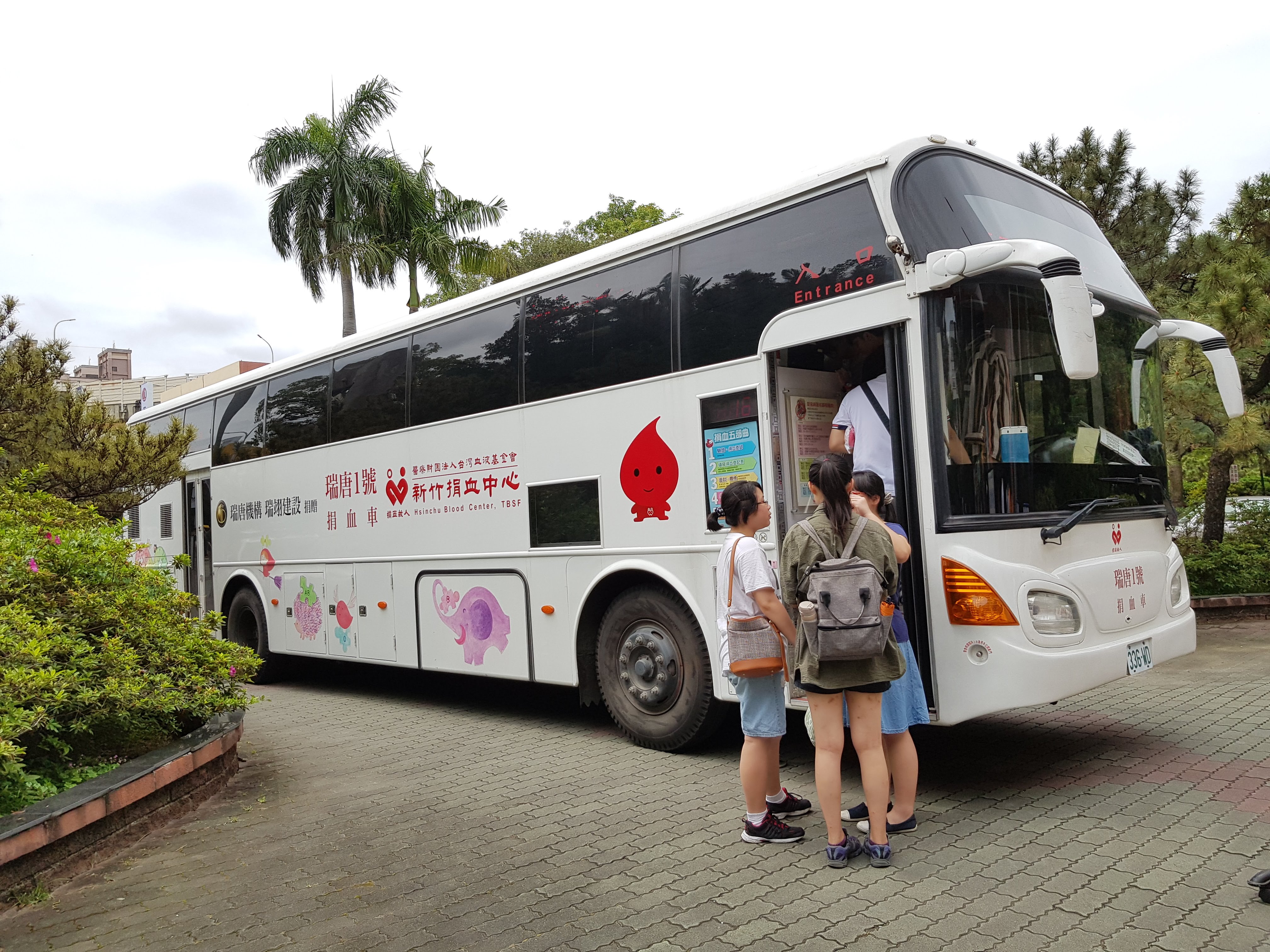 數名學生在捐血車外排隊，等候上車參與捐血活動。